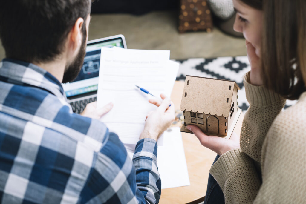 Couple reviewing mortgage application with a model house