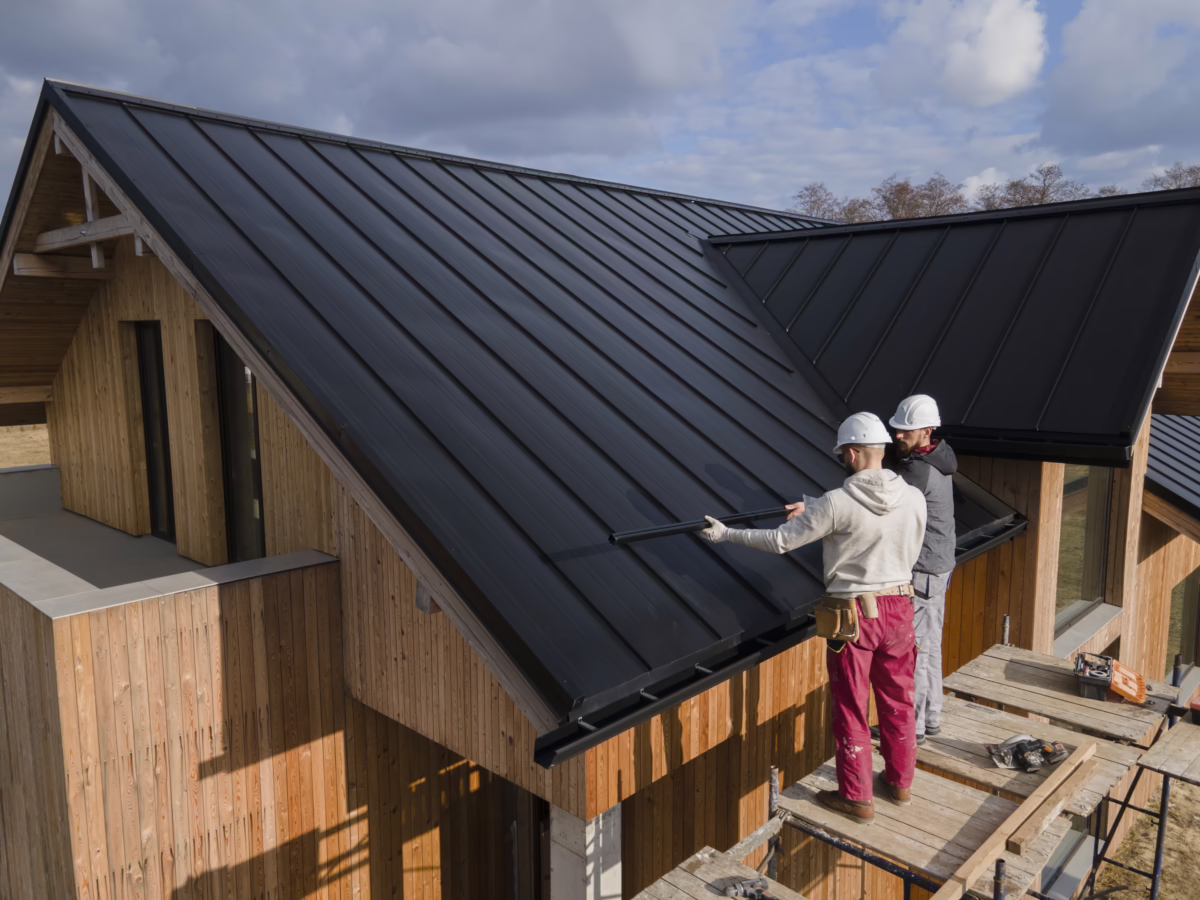 Two roofers working on a metal roof installation