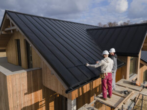 Two roofers working on a metal roof installation